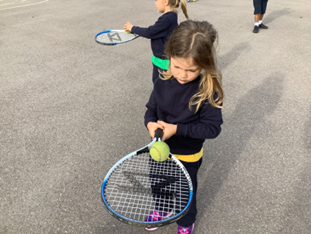 Children balancing ball on tennis racquet